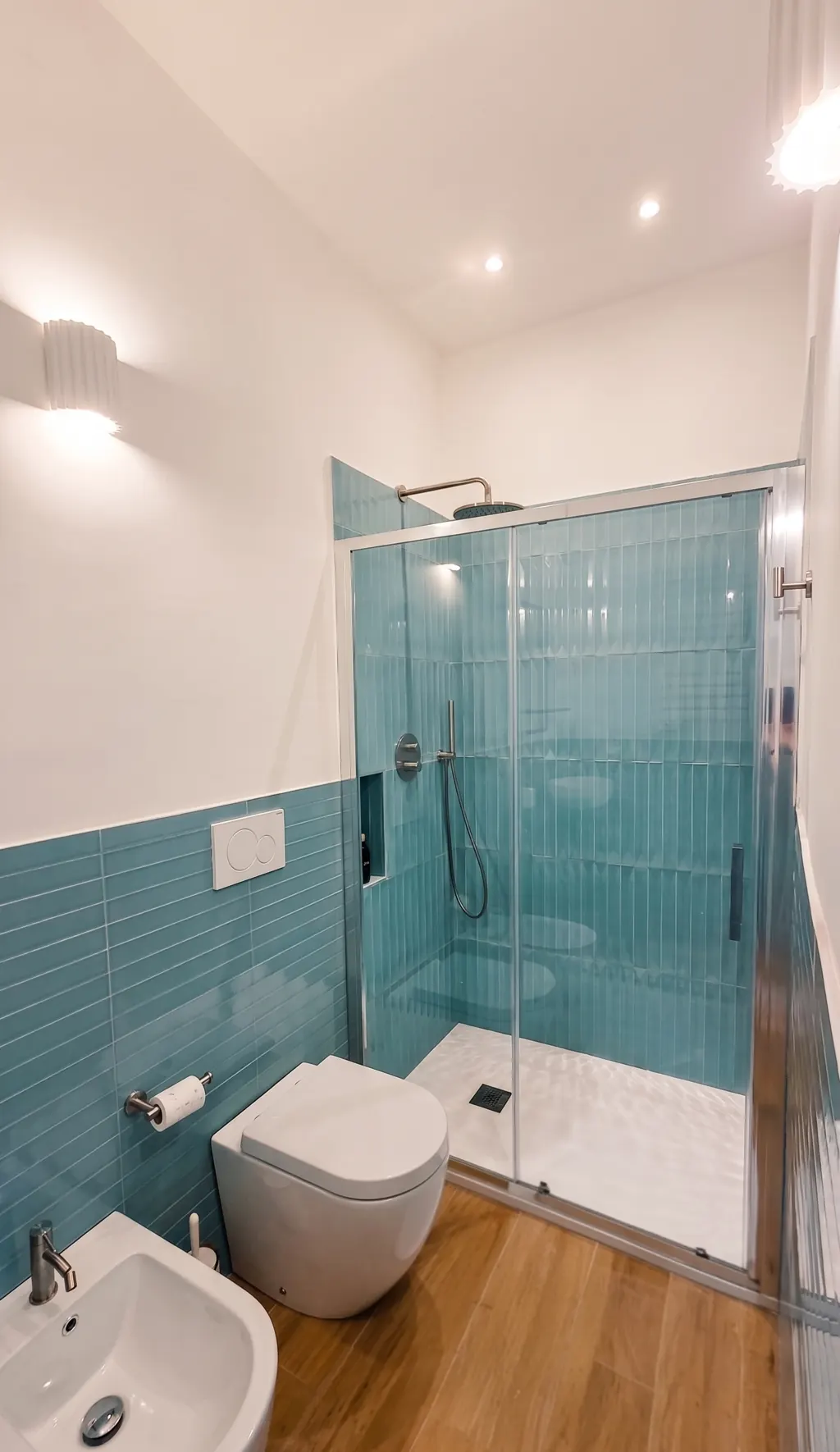 Bagno dell'appartamento ai Navigli con doccia a filo, piastrelle verde acqua e bidet